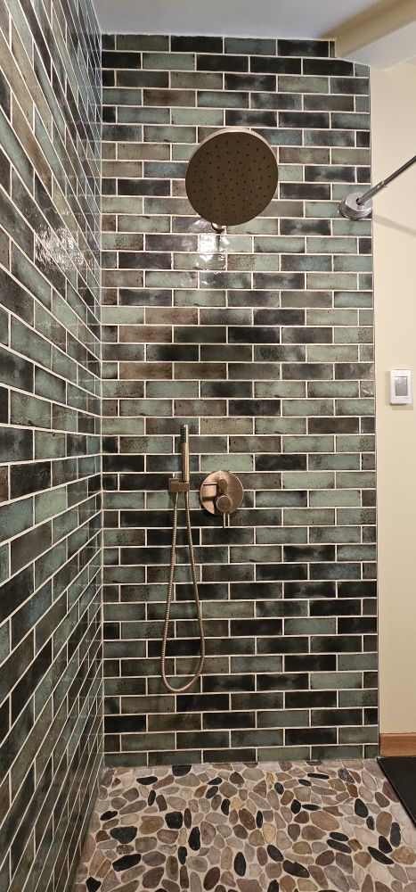 Custom tile shower — handmade teal brick tile, brushed brass fixtures, pebble floor · South Vancouver Island