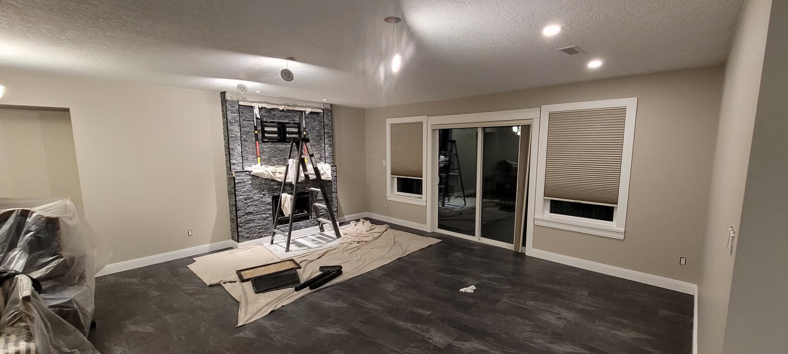 Living room with dark LVP flooring and stone feature wall