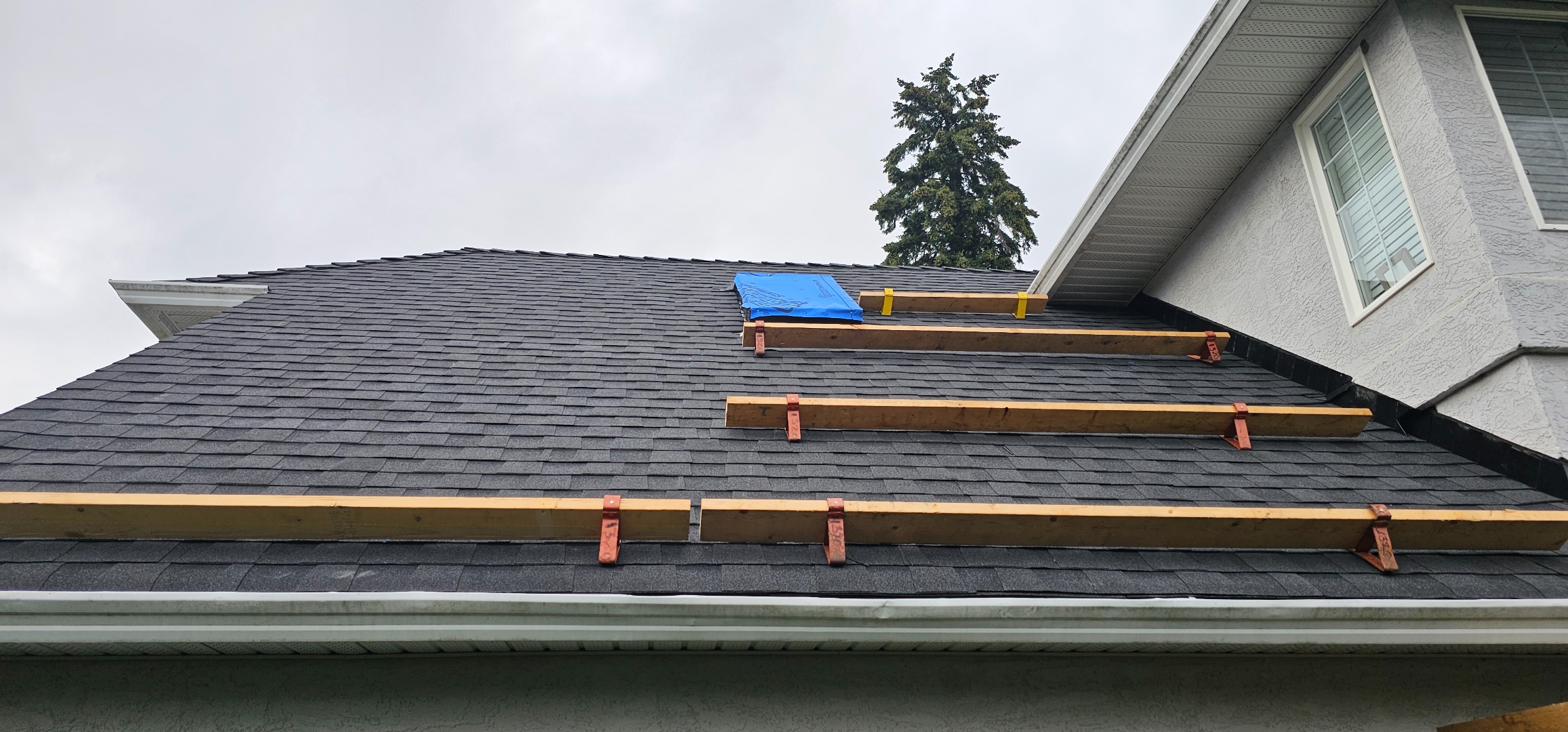 Snow guard installation — copper bracket detail on synthetic tile roof
